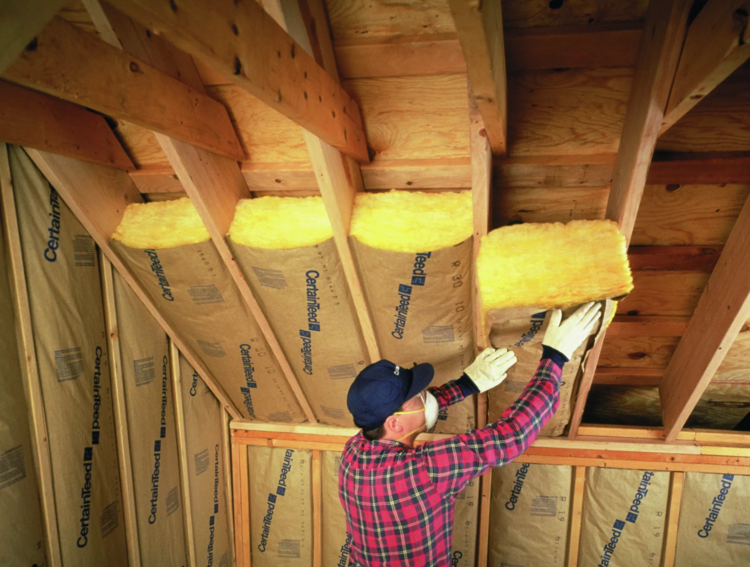 a man installing insulation in attic of a home