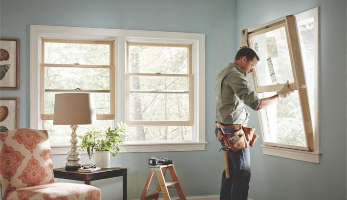 man replacing a window from inside of a house